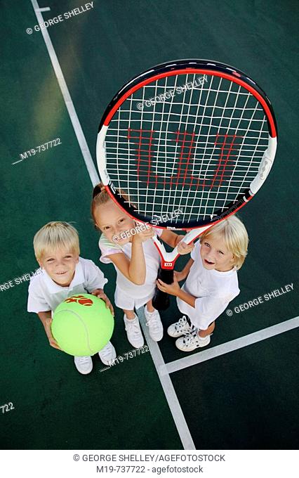 Kids posing with an oversized tennis racket and ball