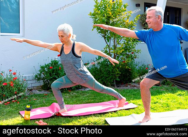 Happy caucasian senior couple practicing yoga together in garden