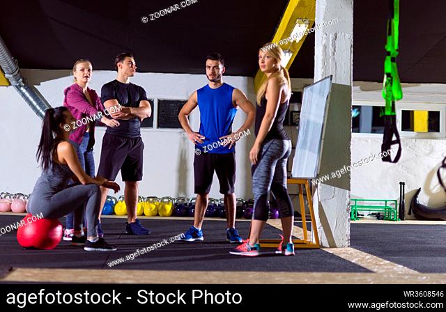 Crossfit training course.group of young athletes getting instructions from trainer before exercise at crossfitness gym