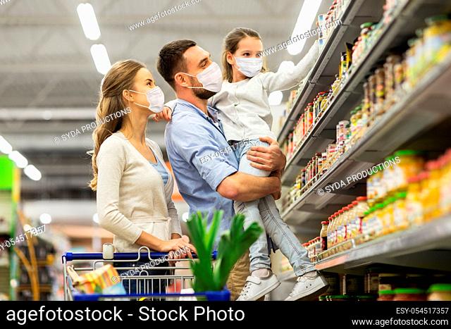 family with shopping cart in masks at supermarket