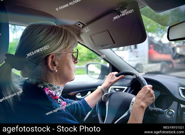 Senior woman wearing eyeglasses driving car