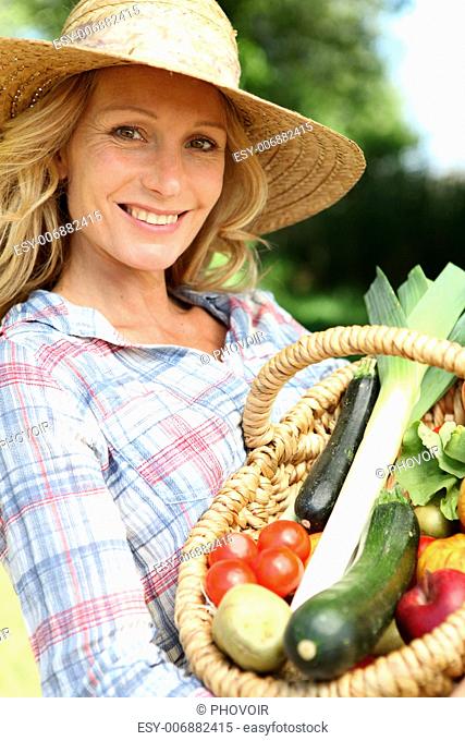 Woman with a straw hat holding basket of vegetables