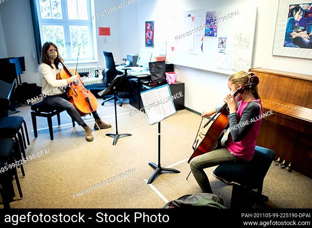 03 November 2020, Lower Saxony, Hanover: Music teacher Sophia Grest (l) and student Jamie sit at a distance during a lesson at the municipal music school and...