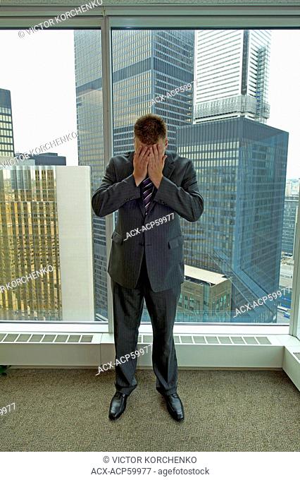 Businessman covering his face in an office in downtown Toronto