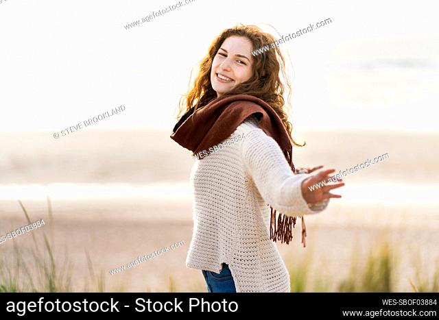 Happy woman with arms outstretched standing at beach