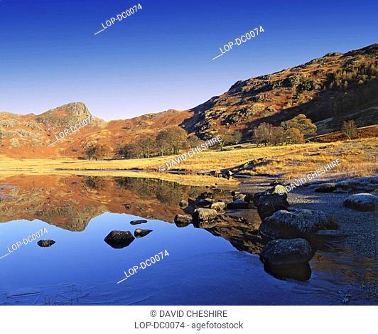 England, Cumbria, Langdale Valley, Looking across the icy shore of Blea Tarn towards the distinctive rounded shape of Side Pike