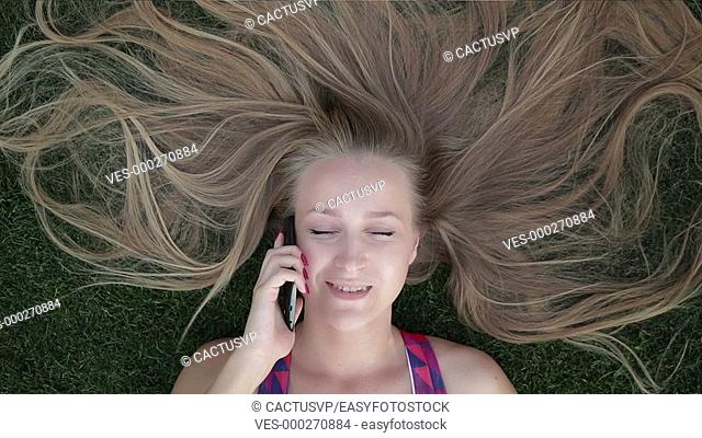 Girl with beautiful blonde hair lying on grass