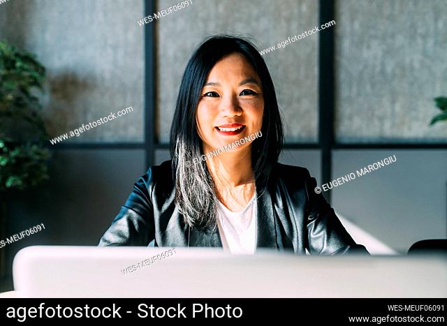 Smiling businesswoman with laptop in office