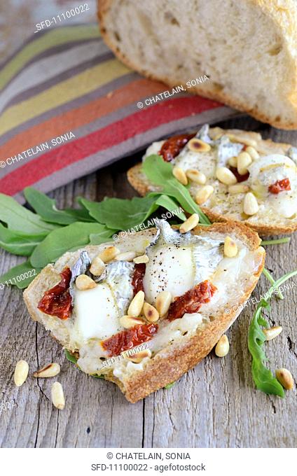 Bruschetta topped with goat's cheese, dried tomatoes and pine nuts