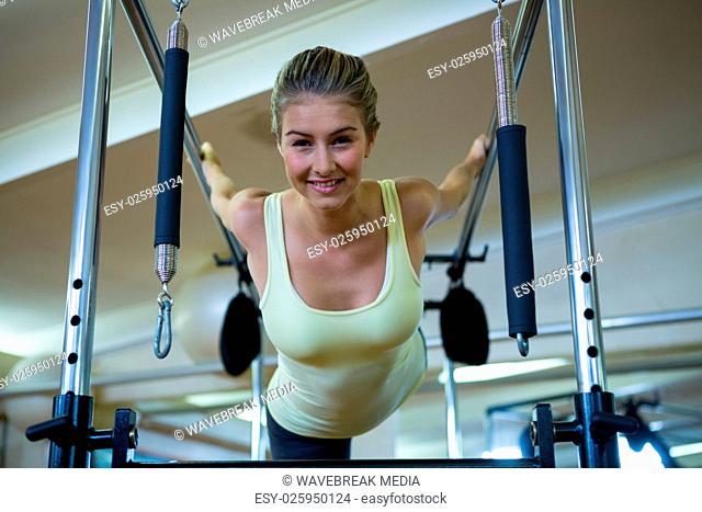 Portrait of beautiful woman performing stretching exercise on pilates cadillac