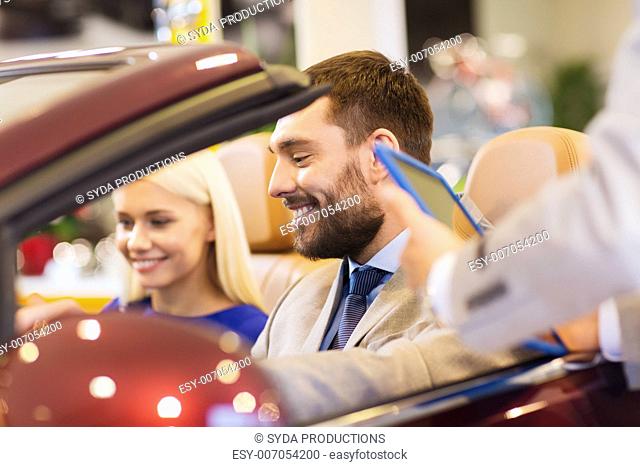 auto business, car sale, consumerism and people concept - happy couple with car dealer in auto show or salon