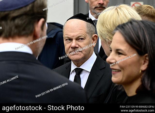 09 November 2023, Berlin: Federal Chancellor Olaf Scholz (M) and Federal Foreign Minister Annalena Baerbock (r) wait in front of a memorial event to mark the...