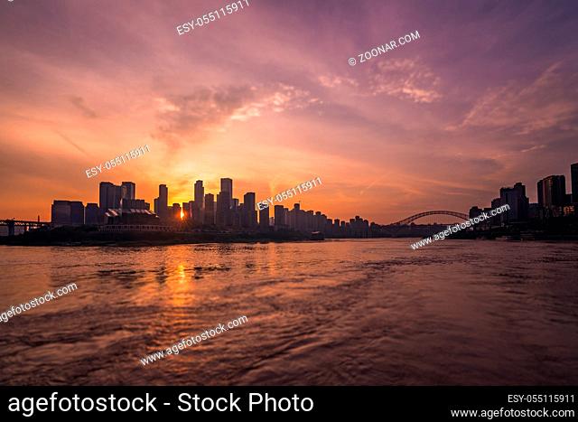 The silhouettes of buildings surrounded by the sea under the sunlight during the sunset in Chongqing, China