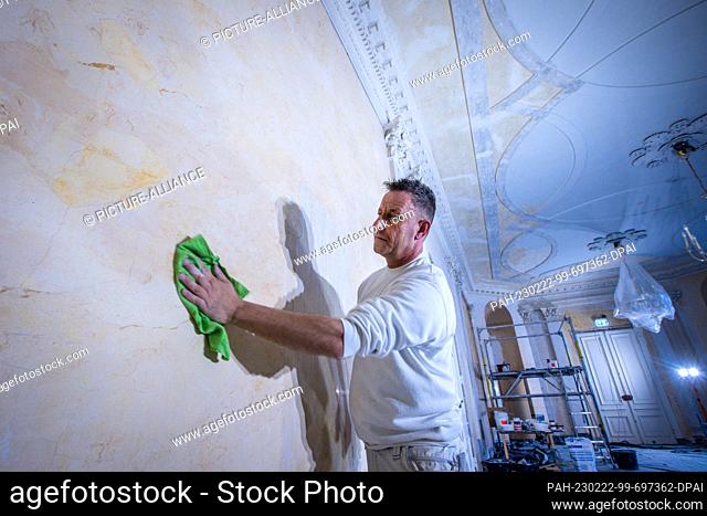 22 February 2023, Mecklenburg-Western Pomerania, Ludwigslust: A replica marble wall is polished with wax by Dirk Westphal from the company Guse Stuck und...