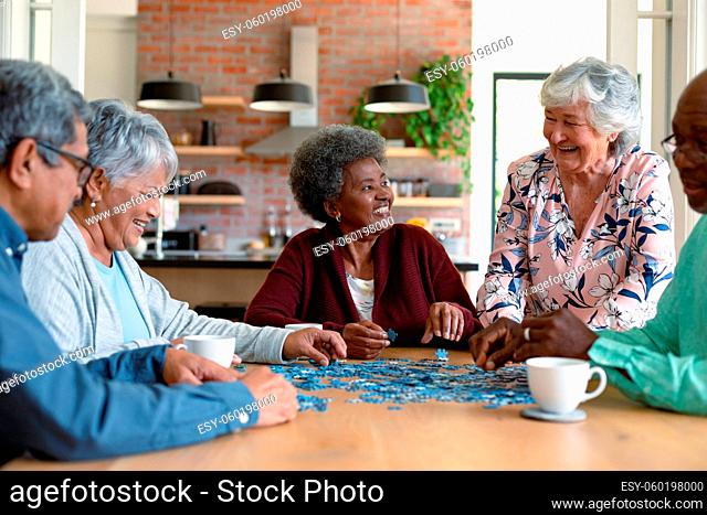 Group of diverse senior male and female friends doing puzzles at home