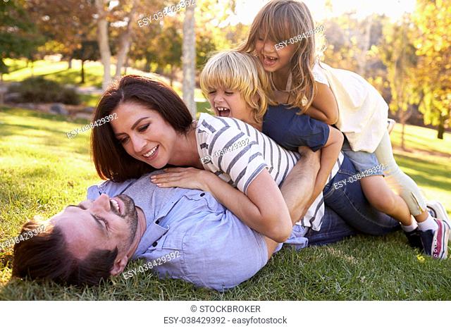 Mother And Children Lying On Father In Park