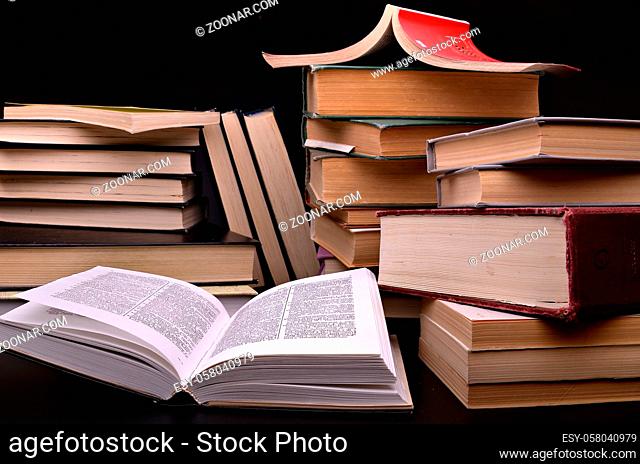 open book and pile of books against a dark background