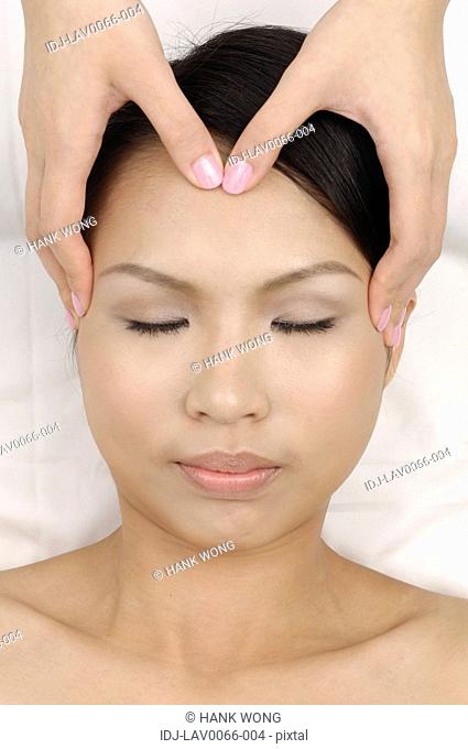 Young woman getting face massage from a massage therapist