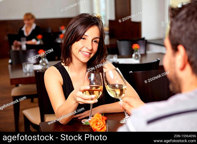 Glückliches Paar im Restaurant prostet sich mit Weingläsern zu