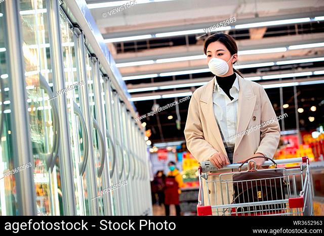 Wearing a mask of young women shopping in the supermarket
