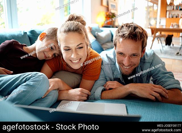 Smiling mother and father watching video with son through laptop in living room