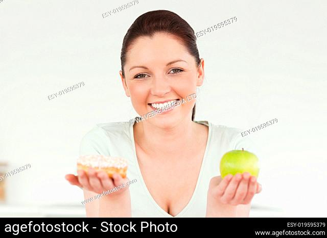 Good looking woman posing while holding a donut and a green appl