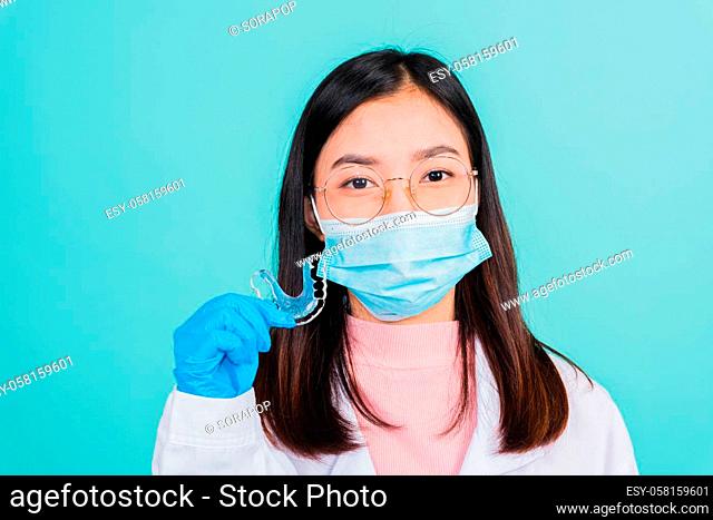 Asian beautiful woman dentist holding silicone orthodontic retainers for teeth on hand isolated blue background, Teeth retaining tools after removable braces