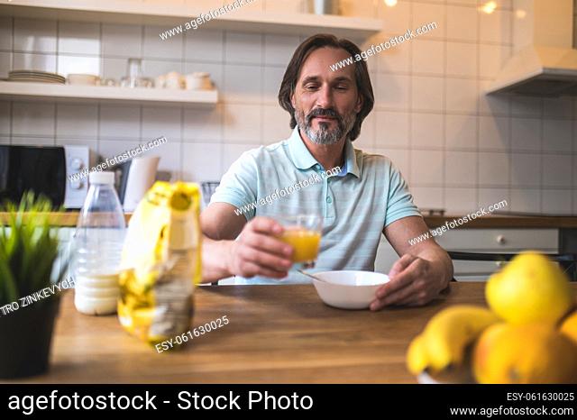 Breakfast. Mature caucasian man sitting at the table and eating breakfast