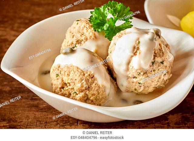 Three Bavarian dumplings in creamy sauce garnished with parsley served as a side dish to a meal