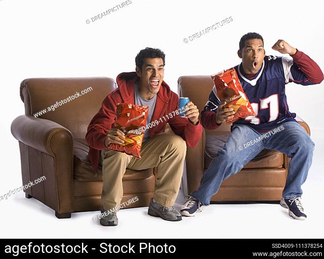 Multi-ethnic men cheering in armchairs
