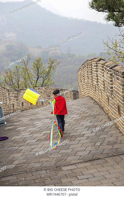 Boy running with a kite on the Great Wall of China, at Mutianyu, Huairou, China