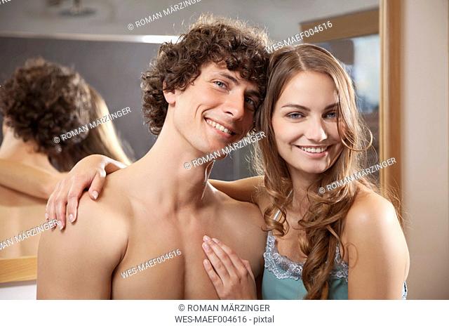 Germany, Bavaria, Young couple embracing in bathroom, smiling, portrait