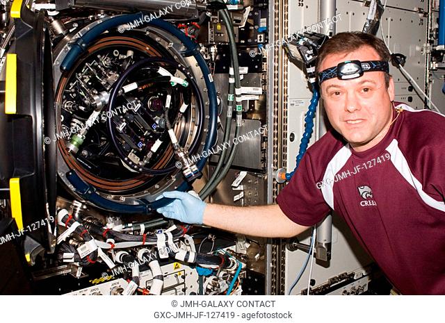 NASA astronaut Ron Garan, Expedition 27 flight engineer, services the Combustion Integrated Rack (CIR) Multi-user Drop Combustion Apparatus (MDCA) in the...