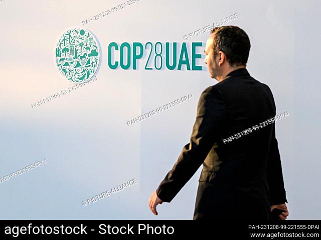 08 December 2023, United Arab Emirates, Dubai: A man walks in front of a wall with the inscription ""COP28UAE"" at the UN Climate Change Conference COP28
