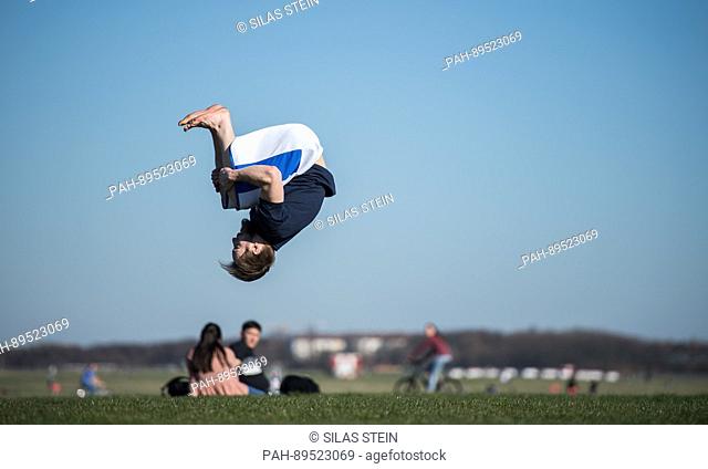 A man performs a backflip on a meadow at the former Tempelhof airport in Berlin, Germany, 27 March 2017. Photo: Silas Stein/dpa | usage worldwide
