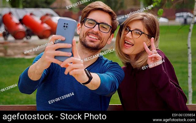 Friends woman and man close up , wearing glasses take selfie with phone, feel happy smiling. Social networking outdoors. Friendship portrait concept
