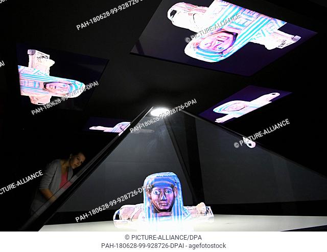 28 June 2018, Hildesheim, Germany: An employee looks at the animated hologram of the mummy Ta- cheru at the ""Ta-cheru, a journey inside the Mummy"" exhibition