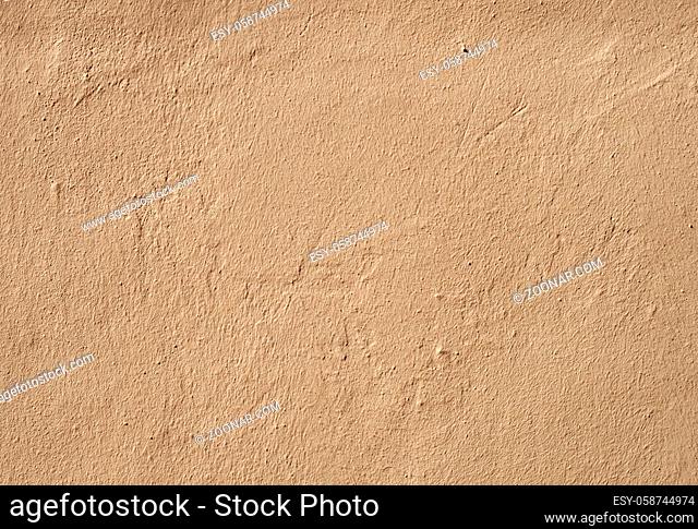 a beige brown rough textured grainy painted cement wall with marks and scratches
