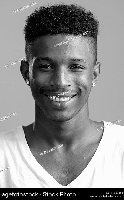 Studio shot of young handsome African man with Afro hair isolated against white background in black and white