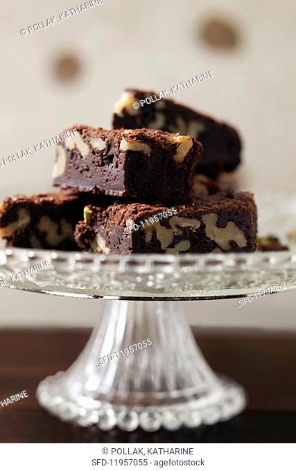 A pile of walnut brownies on a cake stand