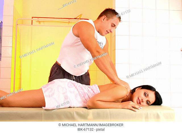 Young woman on a massage couch getting a massage from a masseur