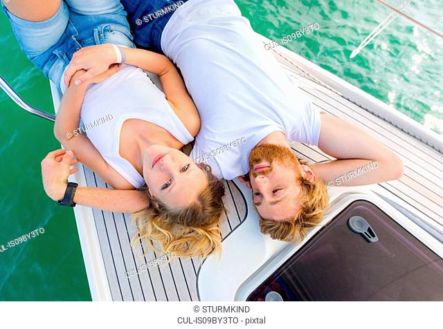Young couple lying on sailboat on Chiemsee lake, overhead portrait, Bavaria, Germany