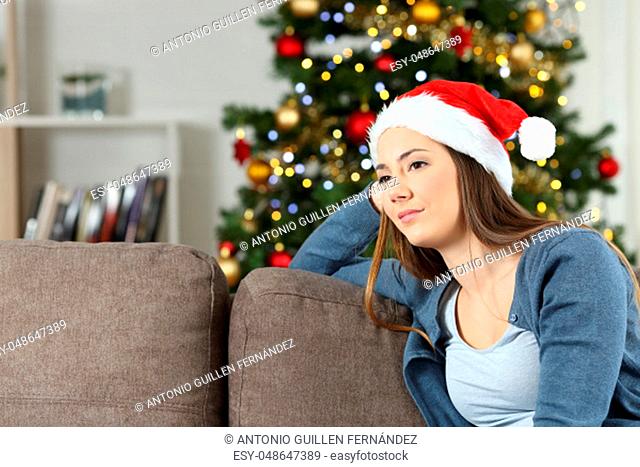 Melancholic pensive woman in christmas sitting on a couch in the living room at home
