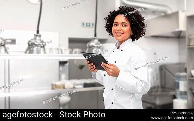 smiling female chef showing tablet pc on kitchen