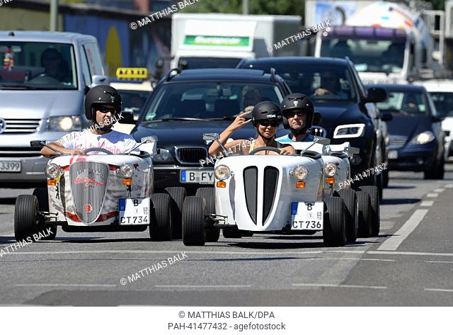 Tour guide Jenny (front) drives with two tourists past the East-Side-Gallery in Berlin,  Germany, 02 August 2013. City tours have been offered in these go-carts...