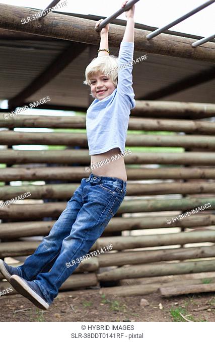 Boy swinging from monkey bars