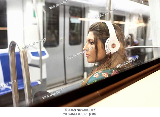 Portrait of young woman listening music with headphones in underground train