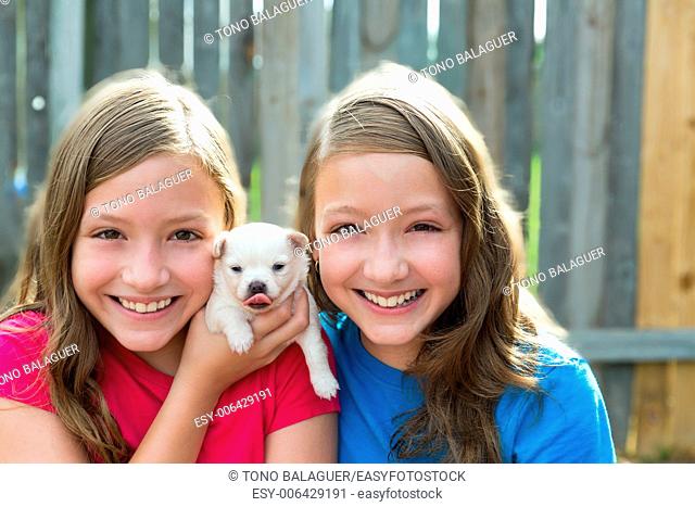Twin sisters and puppy pet dog chihuahua playing together with doggy