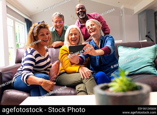 Happy multiracial senior male and female friends taking selfie through smart phone at home