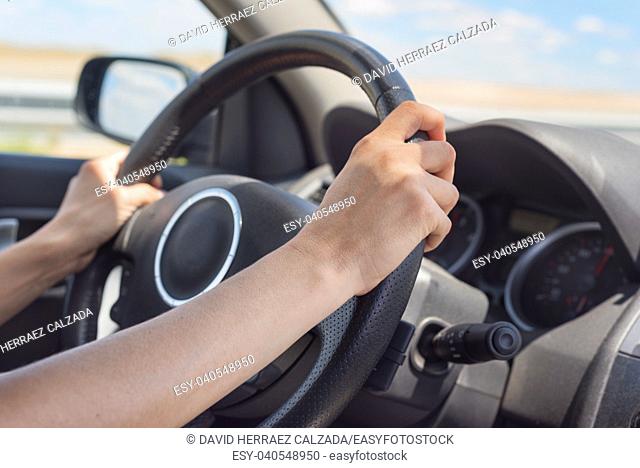 Female hands on the steering wheel of a car while driving